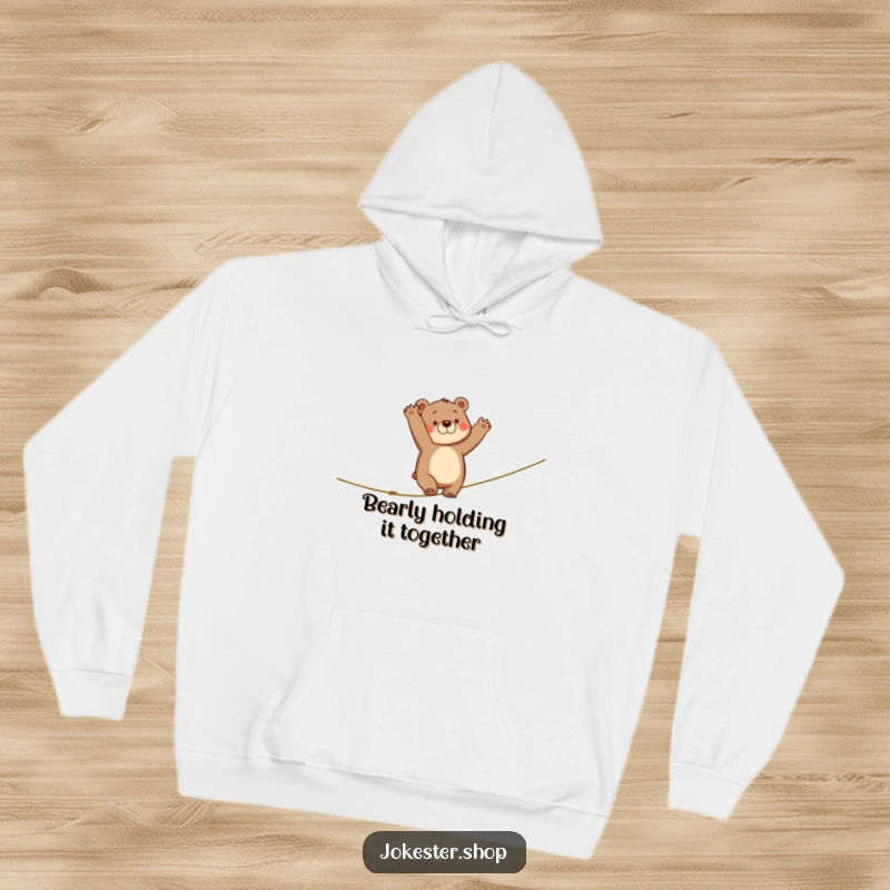 Funny hoodie print of a bear losing balance on a tightrope, arms flailing wildly in a comical and relatable display of clumsiness.